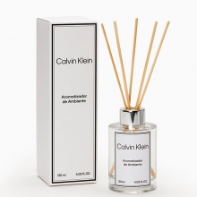 Aromatizador de ambiente Calvin Klein com frasco de vidro elegante, logotipo da marca na frente, varetas de madeira inseridas para liberar essência perfumada sutil no ambiente.